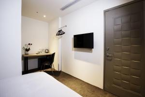 Schlafzimmer mit einem Bett, einem Schreibtisch und einem TV in der Unterkunft Queens Hotel II in Taipeh