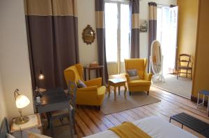 a hotel room with yellow chairs and a bed at Madeleine Bergerac in Bergerac