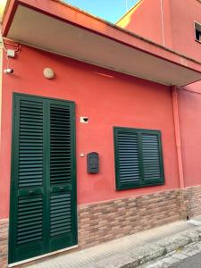 un edificio rojo con dos puertas verdes. en Girasole, en Trepuzzi