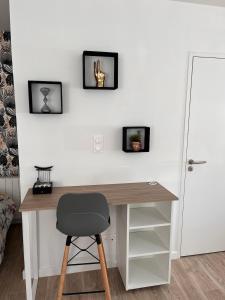 Un escritorio con una silla al lado de una pared con dos cuadros. en Studio récent, entièrement équipé, proche Chantiers et Airbus, en Saint-Nazaire
