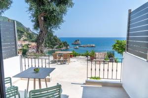 een patio met een tafel en stoelen en de oceaan bij Lithitsa Lofts and Suites in Parga