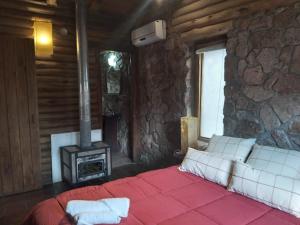 a bedroom with a bed and a stone wall at Rincón Alto Cabañas in Nono +3 photos