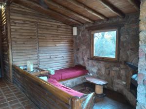 a room with a red bed in a log cabin at Rincón Alto Cabañas in Nono