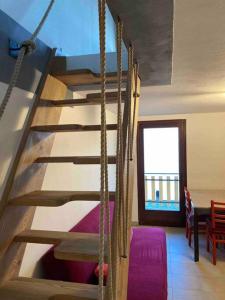 una scala in legno in una camera con divano viola di Baita da Gigli a Bianzone