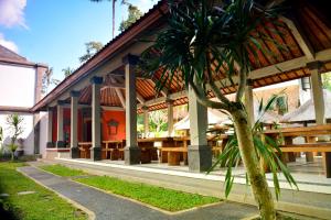 a building with tables and a palm tree in front of it at Full Moon Villa Ubud in Ubud