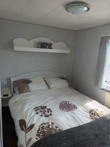a bedroom with a white bed with flowers on it at Carn Kenidjack View Caravan, space, peace and tranquillity in Penzance