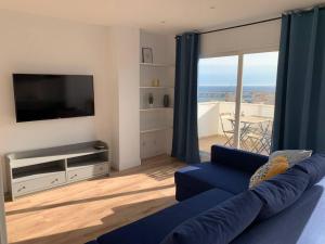 sala de estar con sofá azul y TV en ATICO PASEO DE ALMERÍA en Almería
