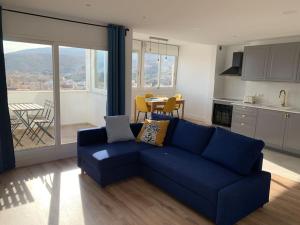 a living room with a blue couch and a kitchen at ATICO PASEO DE ALMERÍA in Almería