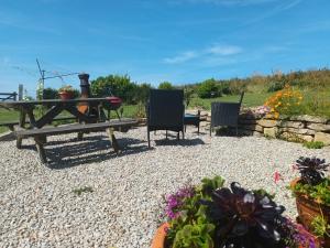 a patio with a picnic table and chairs and flowers at Carn Kenidjack View Caravan, space, peace and tranquillity in Penzance