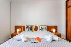a bedroom with a bed with two lamps and two pillows at #167 Santa Eulália by Home Holidays in Branqueira +50 photos