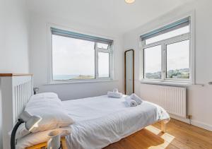 a bedroom with a white bed with two windows at Trecarrack Carthew Way in St Ives