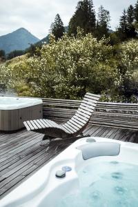 bañera de hidromasaje y sillón en una terraza en Altholz-Apartment en Ramsau