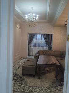 sala de estar con sofá, mesa y lámpara de araña en Apartment, en Ferganá