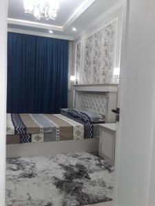 1 dormitorio con 2 camas y cortina azul en Apartment en Ferganá