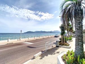 een palmboom aan de kant van een weg naast de oceaan bij Appartement 3 chambres à proximité des plages in Cannes