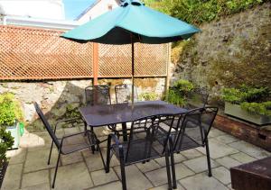 a table and chairs with an umbrella on a patio at Causeway Cottage in Beer