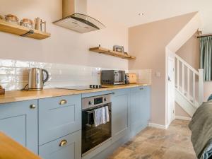 a kitchen with blue cabinets and a stove top oven at The Old Stable At Henley View in Draycott