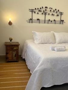 a bedroom with a large white bed and a table at Pousada Pouso de Laura in Tiradentes
