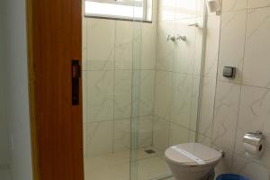 a bathroom with a toilet and a glass shower at Hotel Beirut in Aparecida