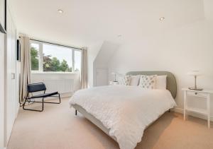 a white bedroom with a large bed and a chair at The Willows in Bromeswell