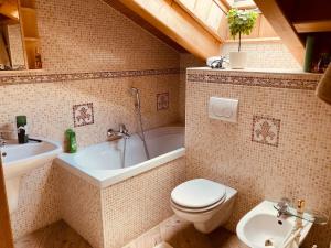 a bathroom with a toilet and a tub and a sink at Appartamento Mazzini in Predazzo
