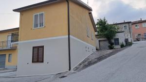 a yellow and white building on the side of a street at "Casa Vacanza Greci" in Greci