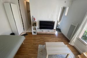 ein Wohnzimmer mit einem Flachbild-TV und einem Tisch in der Unterkunft Cozy love nest near the Seine in Issy-les-Moulineaux