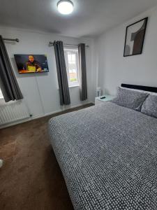 Thamesmead的住宿－TWO BEDROOM LUXURY HOUSE，卧室配有一张床,墙上配有电视。