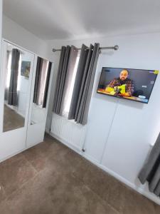 a room with a tv on a wall with windows at TWO BEDROOM LUXURY HOUSE in Thamesmead