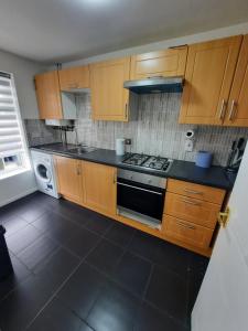 cocina con armarios de madera y horno con fogones en TWO BEDROOM LUXURY HOUSE, en Thamesmead