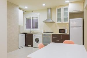eine Küche mit weißen Geräten und einem Tisch mit Stühlen in der Unterkunft Alcam Gold in Barcelona