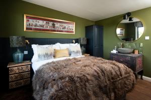 a bedroom with a large bed and a mirror at Bastle Retreats Cabin with hot tub in Duns