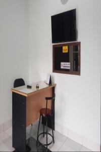 een bureau in een kamer met een tv aan de muur bij SPOT ON 92749 As-sakinah Syariah 2 in Medan