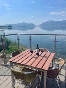 un tavolo in legno con 2 bicchieri di vino sul balcone di Loch Linnhe Waterfront Lodges with Hot Tubs a Glencoe