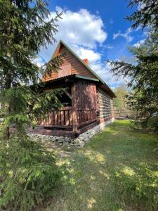 uma cabana de madeira com uma fundação de pedra na relva em Domek Na Roztoczu 