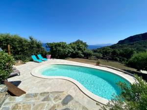 a swimming pool with two blue chairs next to it at Bella Vita Brando in Brando