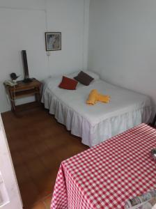 two beds in a room with a red and white table at Amanecer campestre junto al Ceibo. in Burzaco