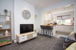 ein Wohnzimmer mit einem TV und einer Küche in der Unterkunft Wheatley Casa, 3 bed, driveway, workspace, wifi, corporates,pets in Doncaster