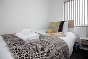 ein Bett mit Handtüchern und ein Tablett mit Essen drauf in der Unterkunft Wheatley Casa, 3 bed, driveway, workspace, wifi, corporates,pets in Doncaster