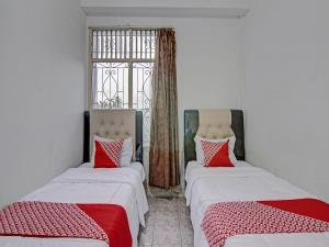 Cette chambre comprend 2 lits avec des oreillers rouges et blancs. dans l'établissement OYO 92746 Wisma 35, 