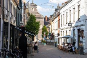 una strada di città con persone sedute ai tavoli sul marciapiede di Huys17 a Hasselt
