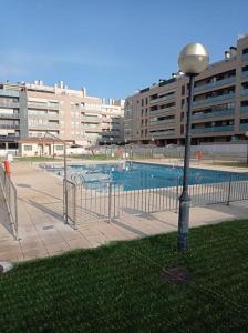 a street light next to a swimming pool with buildings at Acogedor apartamento con piscina y garaje in Huesca