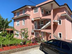a pink building with a car parked in front of it at Apartment & Rooms Lilis in Izola