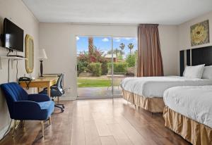 a hotel room with two beds and a desk and a window at Sol Springs Inn in Palm Springs