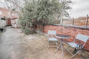 a patio with a table and chairs next to a brick wall at Balby Casa king beds parking workspace wifi corporates pets in Balby