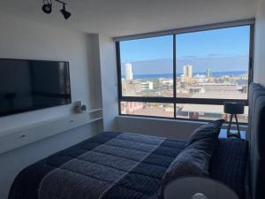 a bedroom with a bed and a large window at Acogedor departamento centro Iquique in Iquique