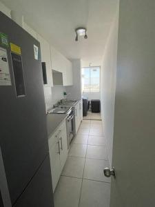 una cocina con armarios blancos y un pasillo con puerta en Acogedor departamento centro Iquique, en Iquique