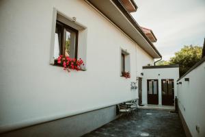 a white building with red flowers in a window at ARINI WHITE HOUSE in Sibiu