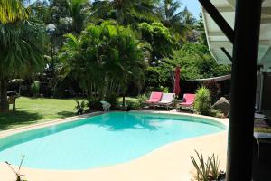 una piscina en un patio con palmeras en THE VILLA BY THE SEA Nouvelle-Caledonie, en Mont-Dore