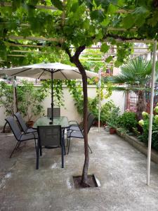 einen Tisch und Stühle unter einem Sonnenschirm im Innenhof in der Unterkunft Къща за гости Мишел in Nessebar
